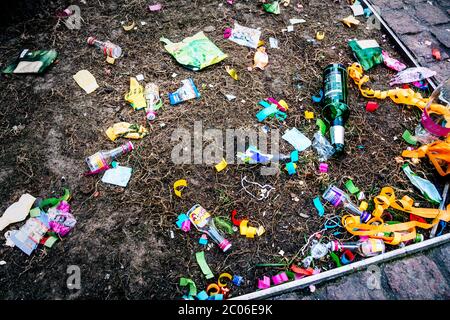 Empty beer bottles, chocolate packagings, festival decorations and other garbage are lying on the sidewalk after the traditional carnival parade. Stock Photo