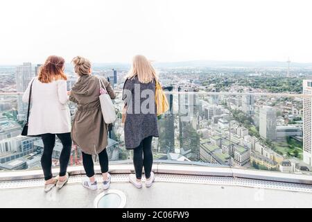 Tourist girls enjoying the beautiful skyline view on a sunny saturday afternoon from the top of Main Tower in Frankfurt am Main - Germany.