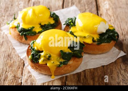 Tasty Eggs Benedict with spinach and hollandaise sauce on a toasted bun close-up on the table. Florentine eggs. horizontal Stock Photo