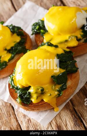 Florentine eggs is a delicious healthy breakfast of poached eggs with spinach and hollandaise sauce on a crispy bun close-up on the table. vertical Stock Photo