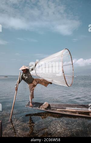 Traditional Fisherman at Inle Lake in Myanmar Barma posing in a typical posture for tourists Stock Photo