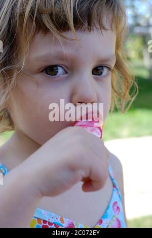 Two and half year old girl eating eating ice cream lolly. Stock Photo