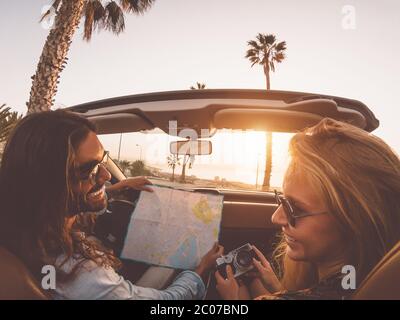 Happy young couple doing road trip in tropical city - Travel people having fun driving in trendy convertible car discovering new places