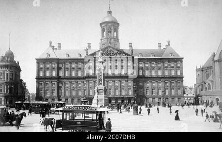 [ 1880s Netherlands - Amsterdam Dam Square  ] — The Royal Palace on the Dam Square in Amsterdam, the Netherlands.  The classical architecture style building was constructed as the city hall in 1655. The main architect was Jacob van Campen (1596–1657).  In the foreground, a horse-drawn streetcar featuring advertising for Van Houten cacao powder can be seen. This series of cars was built by the Amsterdamsche Omnibus Maatschappij in 1884.    19th century vintage albumen photograph. Stock Photo