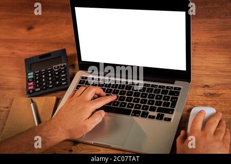 Man's hands using laptop with blank screen on desk in home interior. Stock Photo