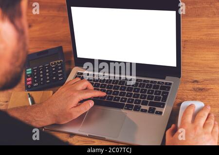 Man's hands using laptop with blank screen on desk in home interior. Stock Photo
