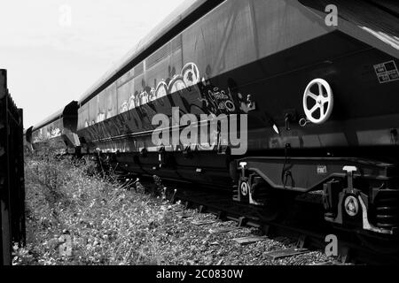 Barry, Vale of Glam, Wales. Black and white photographs of rail trucks lying idle on rails by the old rail-sheds on Barry Waterfront Stock Photo