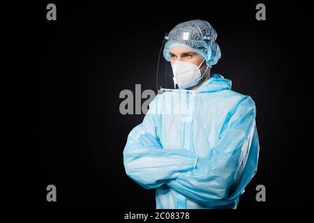 Photo of serious professional guy expert doc virologist arms crossed look empty space wear face mask sterile hazmat blue uniform suit plastic facial Stock Photo