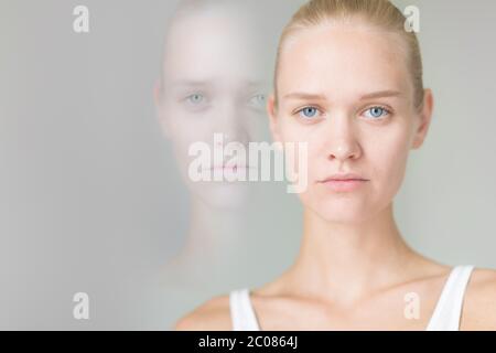 Two faced woman suffering from bipolar disorder and hidden feeling of sadness. Stock Photo