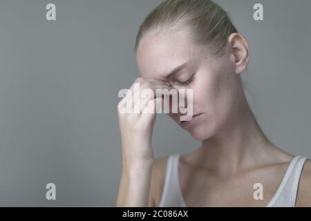 A unhappy stressed out blonde woman looking down suffering from depression. Stock Photo