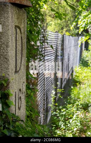 Wegen der Ausbreitung des Corona-Virus haben die Schweiz und Deutschland ihre Grenzen geschlossen. Alter Hintergarten-Grenzzaun mit Grenzstein D16C. K Stock Photo
