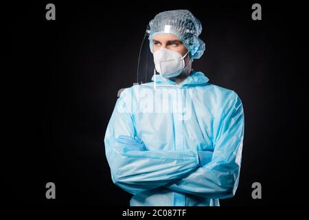 Photo of serious professional guy expert doc virologist arms crossed look empty space wear face mask sterile hazmat blue uniform suit plastic facial Stock Photo