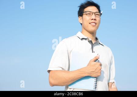 Asian Chinese man doing business walking outside in the city holding his paperwork. Stock Photo
