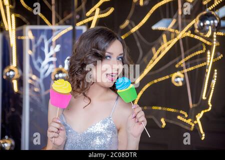 celebration, fun and holidays concept - happy woman posing with party props over festive lights background. New year party. Woman in a Photo Booth Stock Photo