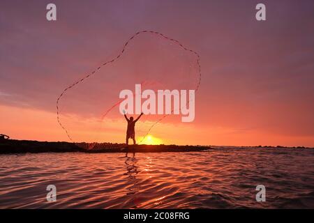 A fisherman throws a fishing net into the sea Stock Photo - Alamy