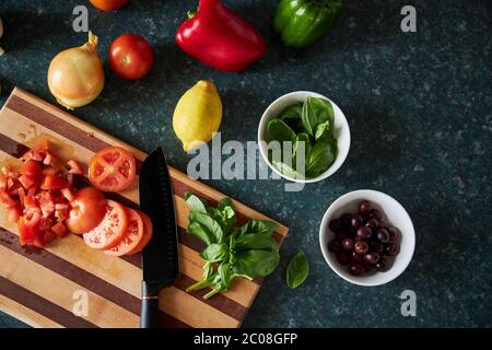 Flat-lay of ingredients being prepared for dinner on wooden chopping board. Stock Photo