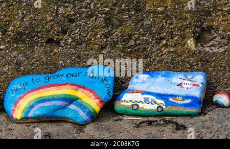 Port Seton, East Lothian, Scotland, UK. 11th June 2020. Covid-19 pandemic symbols created by locals: a line hundreds of feet long on the seafront promenade of colourful and creative hand-painted stones with inspiring messages. It seems to be a phenomenon spreading around the towns & villages of East Lothian. Stones with a rainbow symbol of hope and one depicting rescue services including RNLI lifeboat and the coastguard search and rescue service with a helicopter Stock Photo