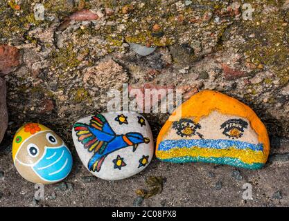 Port Seton, East Lothian, Scotland, UK. 11th June 2020. Covid-19 pandemic symbols created by locals: a line hundreds of feet long on the seafront promenade of colourful and creative hand-painted stones with inspiring messages. Stones with a face mask and bird Stock Photo