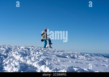 Girl in snowboard-wear is funny walking on top of a mountain peak in Hasliberg Switzerland. Concept for funny walk. Stock Photo