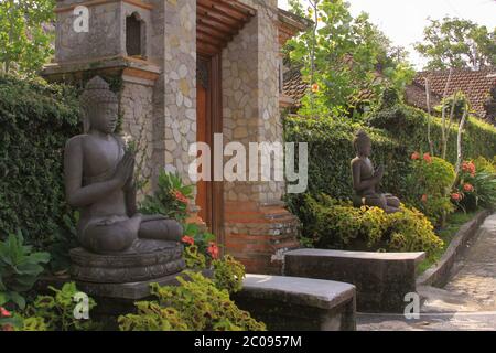 Door or gate to enter into traditional balinese garden architecture detail. Ubud gate guarded by Buddha statues at entry in balinese garden. Travel ph Stock Photo