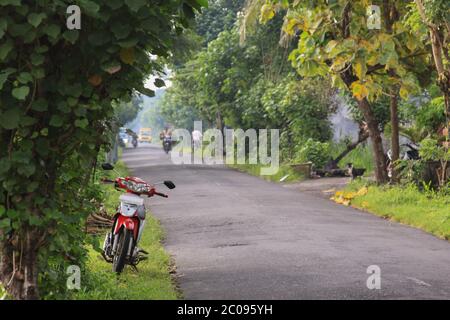 Red scooter on Amed road in Bali, Indonesia. Amed has become a popular tourist destination and is located on the east coast of Bali. Scooter is parked Stock Photo