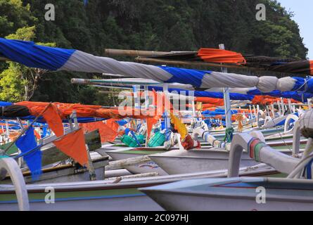 Jukung boat on cloudy day in Bali, Indonesia. Here are some sailboats parked side by side in a little fishing village in Bali. The boat is fitted with Stock Photo