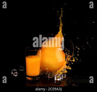 Splash in orange juice in a transparent jug on a black background Stock Photo