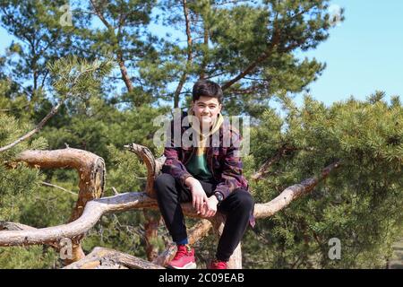 White guy sitting on a pine tree trunk Stock Photo