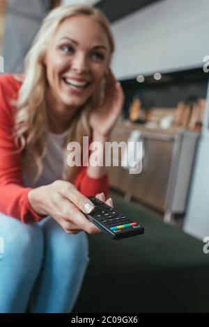 selective focus of excited woman laughing while watching tv at home Stock Photo