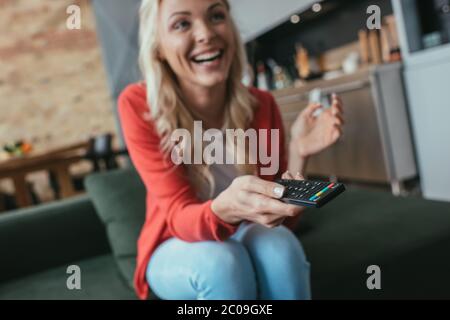 selective focus of cheerful woman laughing while watching tv at home Stock Photo