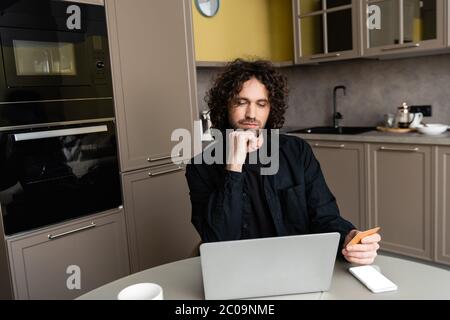 thoughtful freelancer holding credit card near laptop and smartphone with white screen Stock Photo
