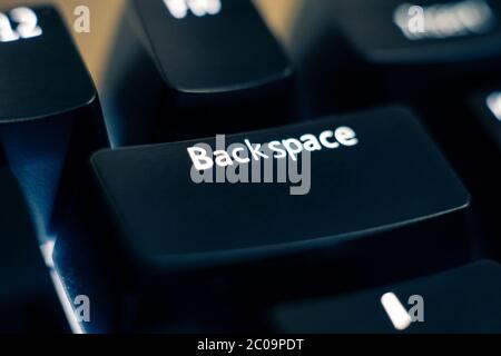Macro photo of the backspace key on a mechanical switch keyboard. The letters are etched on black plastic ABS keycaps to reveal white led backlight. Stock Photo