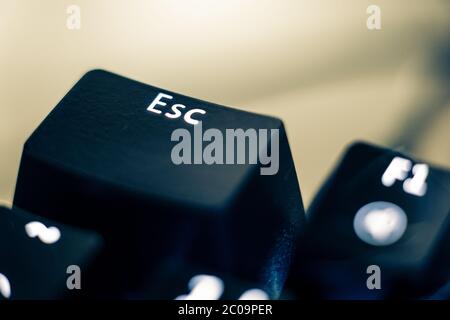 Macro photo of the escape key on a mechanical switch keyboard. The 'ESC' letters are etched on plastic ABS keycaps to reveal the white led backlight. Stock Photo
