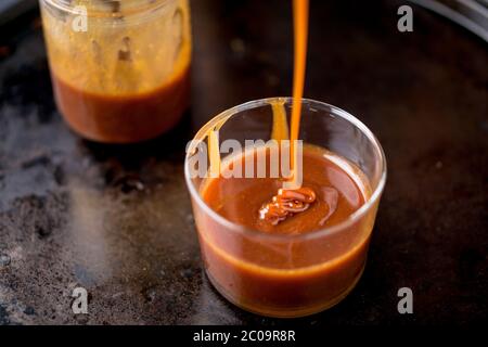 Caramel sauce dripping in a jar. This sweet and delicious caramel sauce can be used as topping to add flavor to cakes, ice cream and many other desser Stock Photo