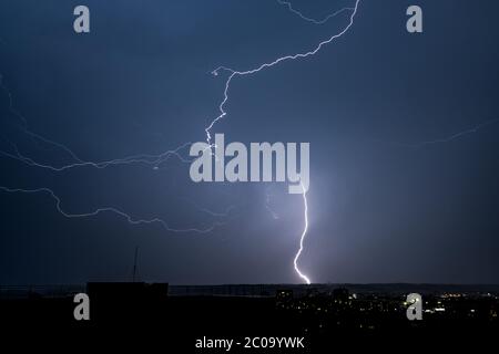 Beautiful night landscape with thunderstorm lightning bolts with rain and stormy sky over the city Stock Photo