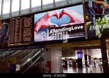 Roma Termini railway station, almost deserted at the time of  Covid 19 Coronavirus. Message on the big led screen billboard, hands forming a heart. Departures information display board. Phase 2, two, 2020. Rome, Italy, Europe, European Union, EU