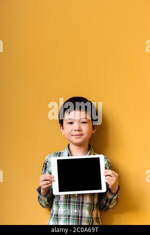 cute asian boy holding digital tablet with blank screen on yellow Stock Photo