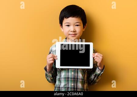 asian boy holding digital tablet with blank screen on yellow Stock Photo