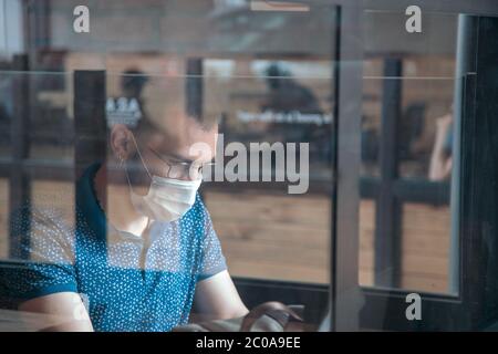 Young man works in a public cafe with protective mask Stock Photo