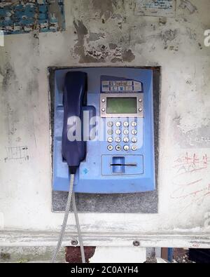 Image of an old and scratched vintage public payphone.Blue old payphone. Stock Photo