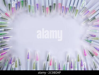 Frame made of many pens and markers of different colors and shades lying on a white sheet of the album.there is a place for text. High quality photo Stock Photo