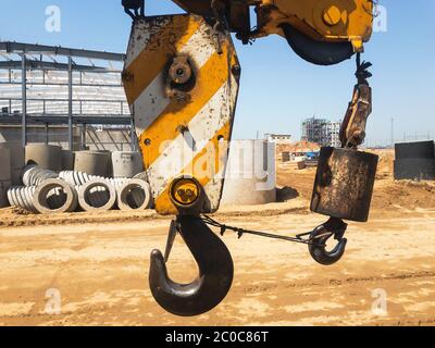 Crane hook with yellow stripes on the background of an empty construction site. High quality photo Stock Photo