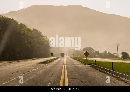 Sunrise light over the road on the morning with a few fog. Stock Photo