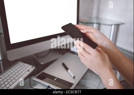 Female hands using smart phone in interior workplace, freelance business woman using cell phone at office desk, working from home using smart phone an Stock Photo
