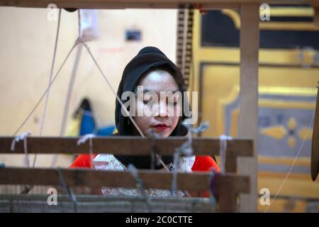 A young, indigenous, ethnic Cham woman makes her income from traditional weaving in her village near Chau Doc, southern Vietnam. Stock Photo