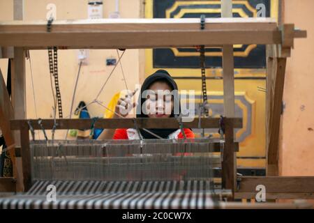 A young, indigenous, ethnic Cham woman makes her income from traditional weaving in her village near Chau Doc, southern Vietnam. Stock Photo