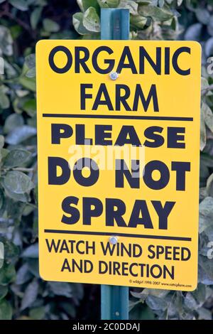Posted sign at Orange orchard,  'PLEASE DO NOT SPRAY - WATCH WIND SPEED AND DIRECTION',  Organic citrus orchard, California. Stock Photo