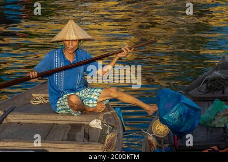 Locals rowing a boat on the Thu Bon river in Hoi An historical town, a UNESCO world heritage. Stock Photo