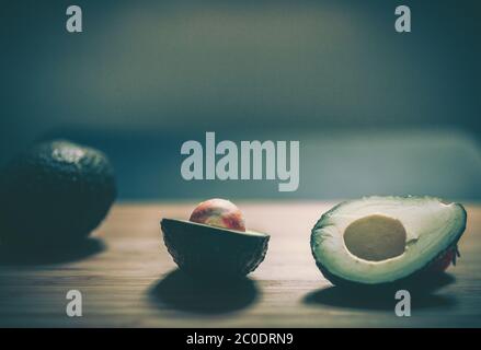 Whole and sliced fresh avocados on wooden table Stock Photo