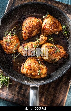 Baked chicken thigh in a pan with rosemary and salt. Dark wooden ...